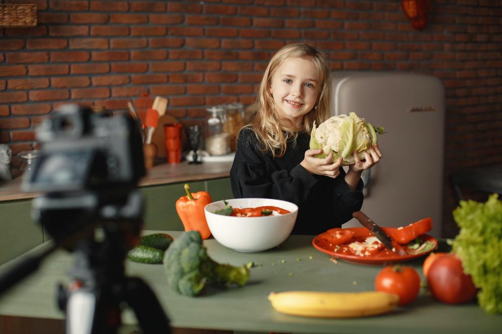 Kleines Mädchen ca. 6 hält Blumenkohl hoch und grinst dabei.
Um Sie herum sind weitere Gemüsesorten wie Paprika, Brokollie, Tomaten.
#zcatering #caterer #berlin #kitacaterer #schulcaterer #regional #qualitativ #gesund #biocaterer #Mittagessen #Ernährung #ausgewogeneErnährung #Berlinmitte #BerlinerFamilienunternehmen